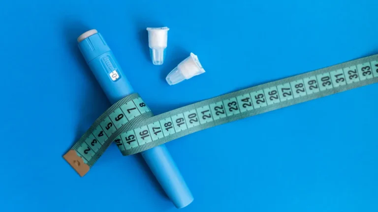 Modern drug pen injection Ozempic for weight loss with body measuring tape and needles on a blue background