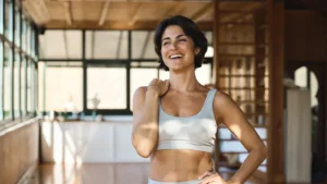 Happy young Latin woman yoga coach laughing standing in yoga gym studio.